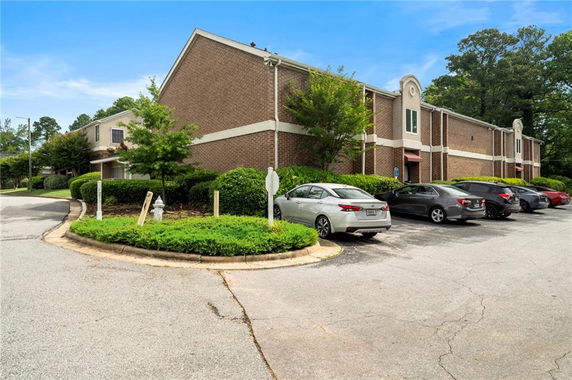 View of a parking area in front of a two-story brick building.