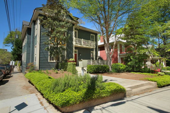 Front view of a two-story house with a balcony and green siding.