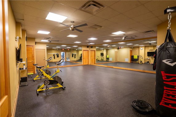 Interior of a gym room with exercise bikes, punching bag, and mirrors on the wall.