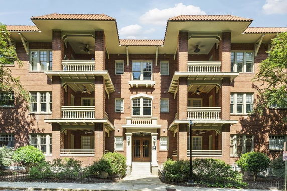 Front view of a multi-story brick apartment building with balconies.