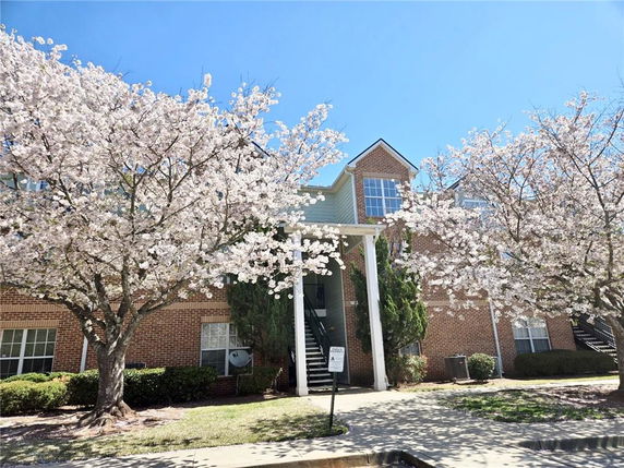 Front view of a two-story brick building with large windows and cherry blossom trees in bloom.
