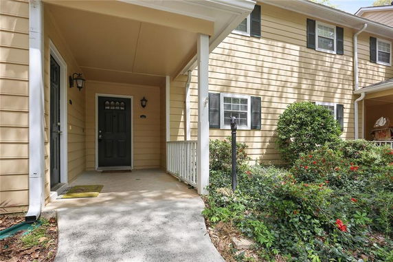 Front view of a house with a porch entrance and black door.