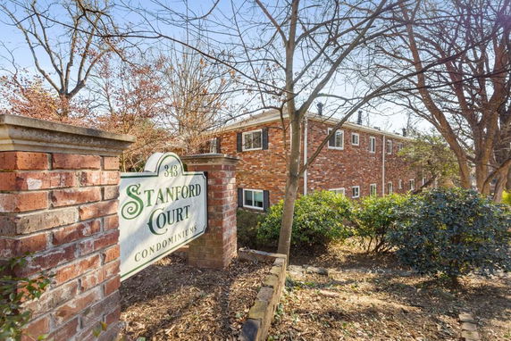 Side view of a brick condominium building with a sign reading 'Stanford Court Condominiums.'
