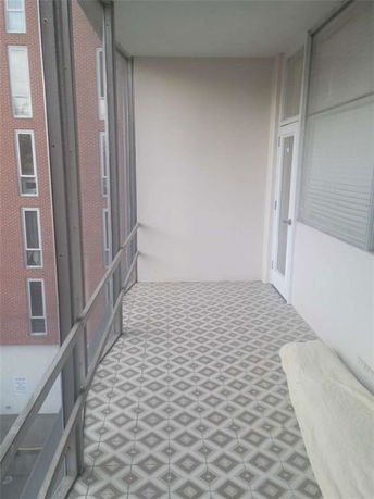 Balcony with tiled floor and view of adjacent building.