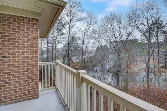 View from a balcony overlooking a wooded area and a body of water.