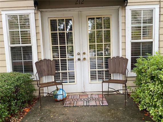 Front view of a house with double french doors and two chairs on a porch.