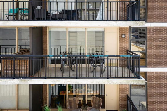 Front view of a building with multiple balconies featuring outdoor furniture.