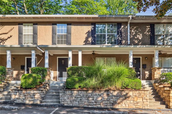 Front view of a two-story townhouse with a covered porch and stone steps leading to the entrance.