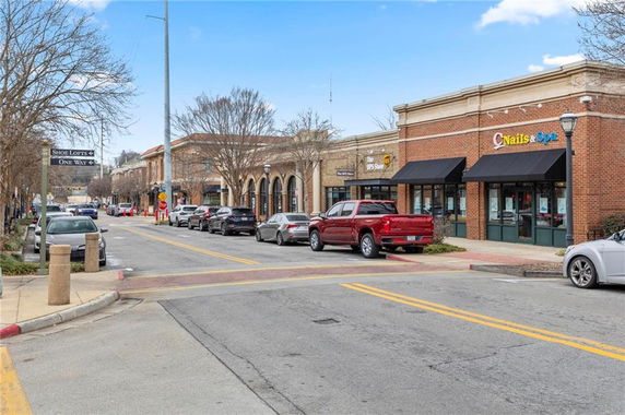 Street view with multiple storefronts including a Nails & Spa and The UPS Store in a small shopping area.