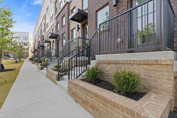 Front view of a row of modern townhouses with brick exteriors and small staircases leading to each entrance.