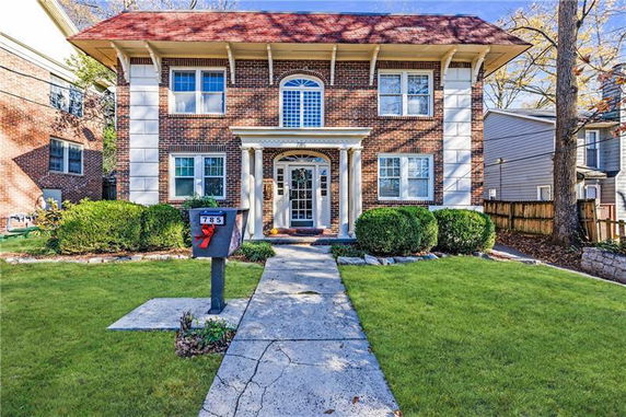 Front view of a two-story brick house with a central entrance and columns.