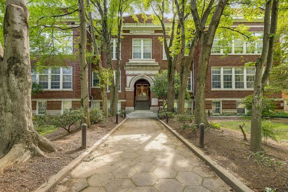 Front view of a brick building with large windows and an arched entrance.