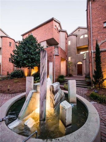 Front view of a multi-story building with brick and stucco facade and a decorative fountain in the courtyard.