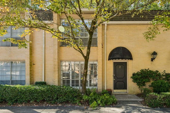 Front view of a two-story brick townhouse with a black door and awning.