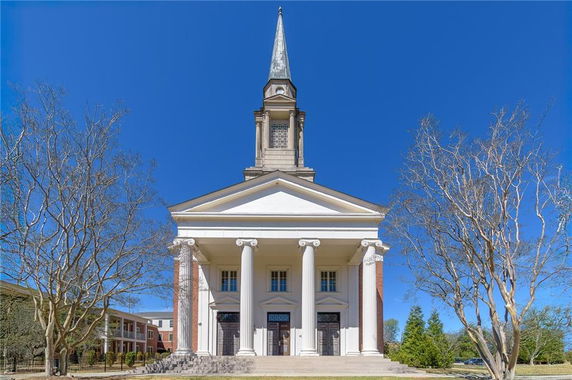 Front view of a church with large columns and a tall spire.