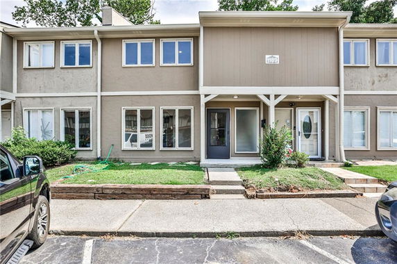 Front view of a two-story townhouse with multiple windows and a small front yard.