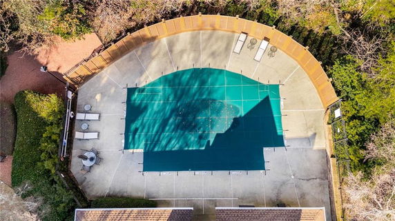 Top view of a covered outdoor swimming pool with surrounding patio and seating.