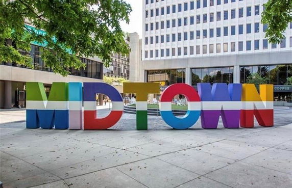 Front view of a multi-story office building in an urban area with 'MIDTOWN' sign in front.