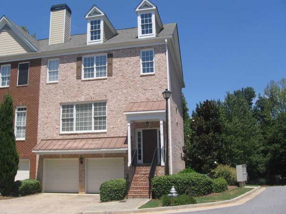 Front view of a multi-story brick townhouse with double garage.