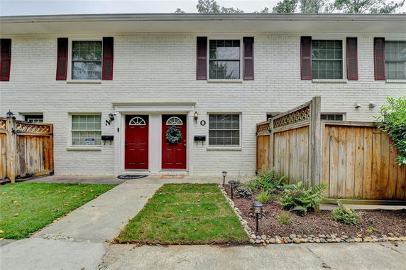 Front view of a two-story townhouse with red doors and white brick facade.