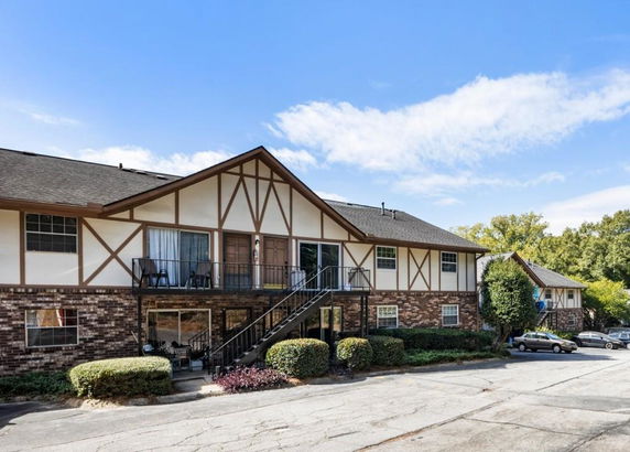 Front view of a two-story residential building with a brick facade and decorative wood trim.