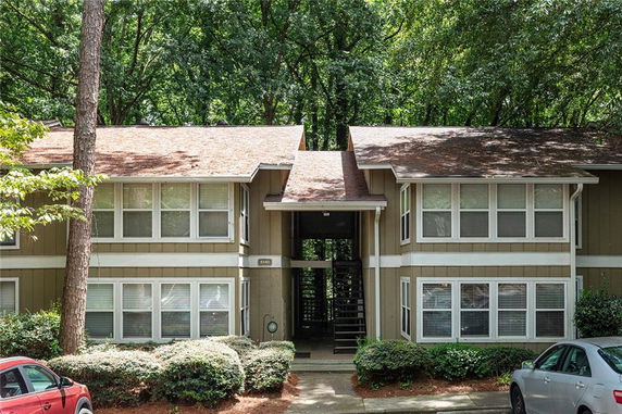 Front view of a two-story house with brown siding and multiple windows under a gabled roof.