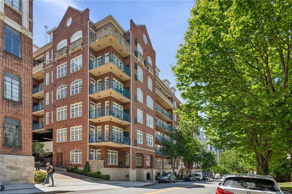 Front view of a multi-story brick apartment building with balconies.