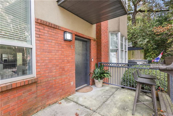 Front view of a brick-walled house with a small patio area and seating.