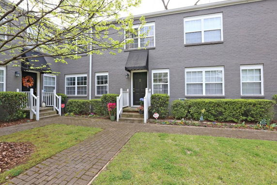 Front view of a two-story brick townhouse with white-framed windows.