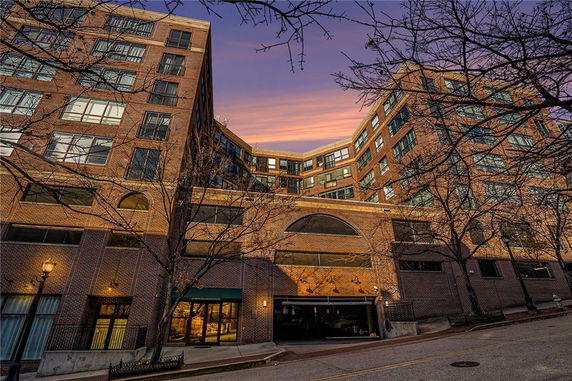 Front view of a multi-story brick building with large windows and an entrance.