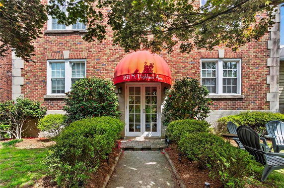 Front view of a brick building with a red awning and white-framed windows.