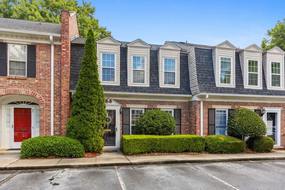 Front view of a two-story townhouse with brick facade and multiple windows.