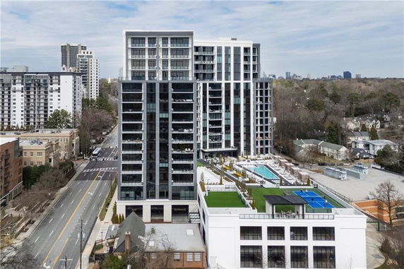 Front view of a tall modern apartment building with balconies and glass facade.