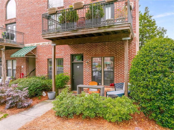 Front view of a brick building with balconies and a small outdoor seating area.