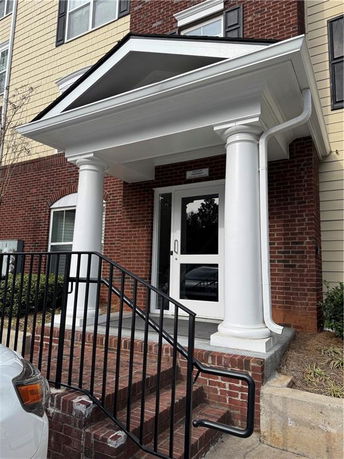 Front view of a building entrance with white columns and brickwork.