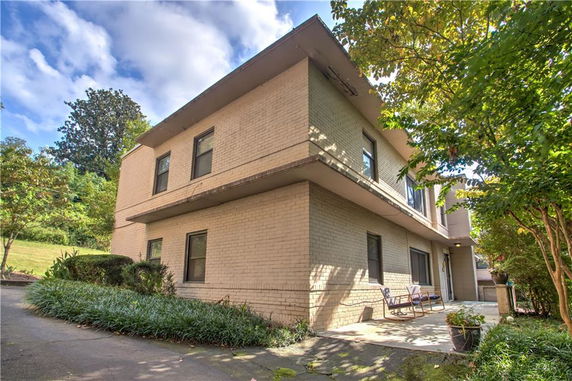 Front view of a two-story house with a flat roof and patio.