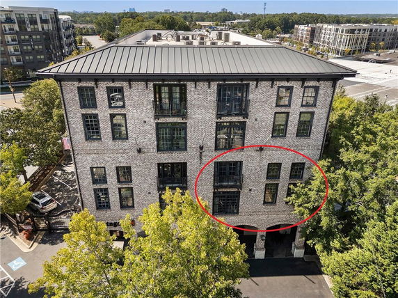 Front view of a multi-story brick building with large windows and a metal roof.