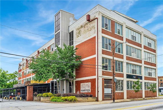 Front view of a four-story brick building with large windows and an external staircase.