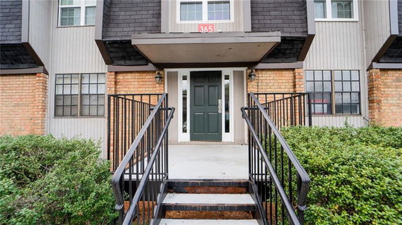 Front view of a multi-story building with steps leading to a dark front door.