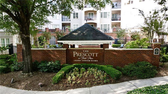 Front view of a multi-story luxury condominium complex with a sign and landscaped entrance.