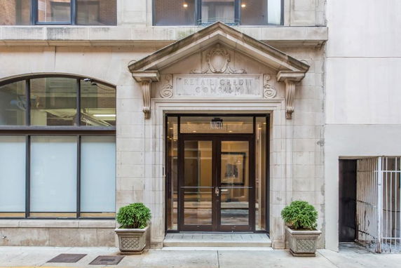 Front view of a building entrance with stone arch and glass doors.