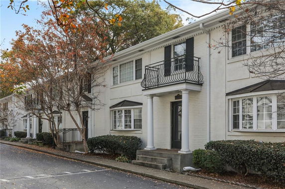 Front view of a two-story townhouse with white exterior and black shutters.