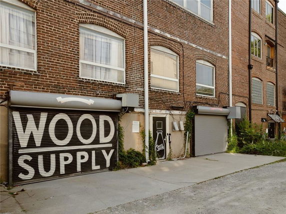 Front view of a brick commercial building featuring a roller shutter labeled 'Wood Supply'.