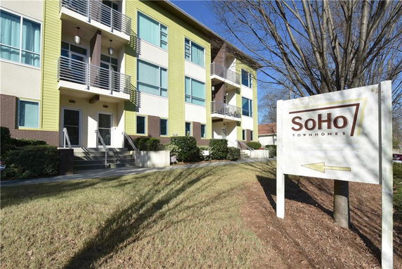 Front view of a modern multi-story townhome building with balconies.