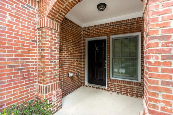 Front view of a brick house entrance with an arched doorway.
