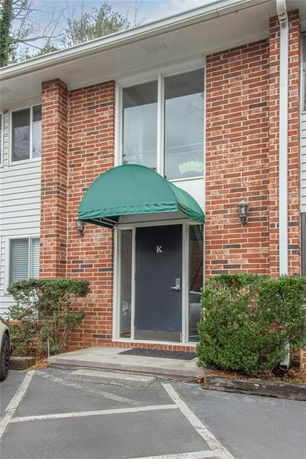 Front view of a multi-story building entrance with brick facade and green awning.