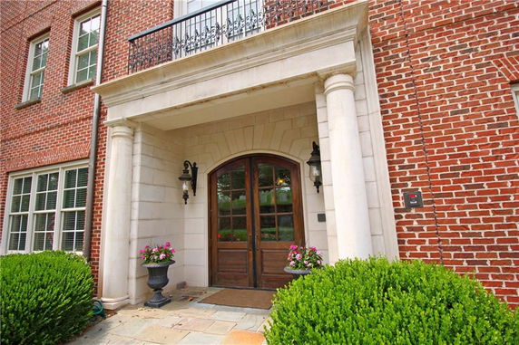 Front view of a brick house entrance with columns and wooden door.