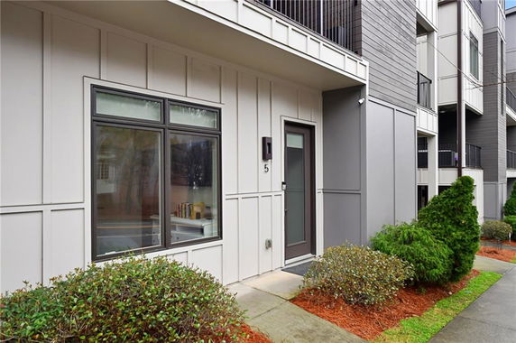 Front view of a modern multi-story building with large windows and a door labeled with number 5.