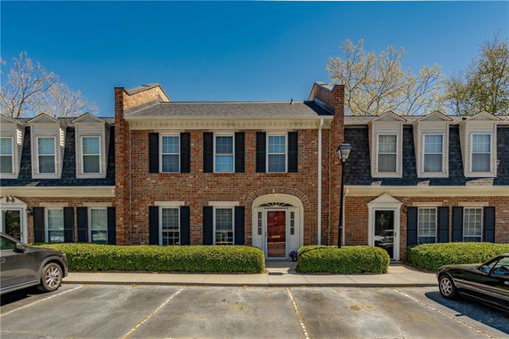 Front view of a two-story brick townhouse with multiple windows and a central entrance.