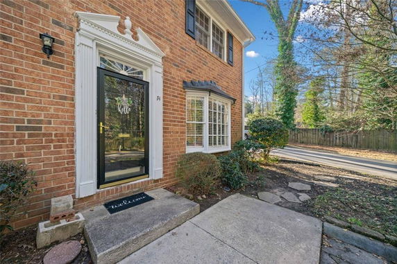 Front view of a brick house with a decorative door frame and bay window.